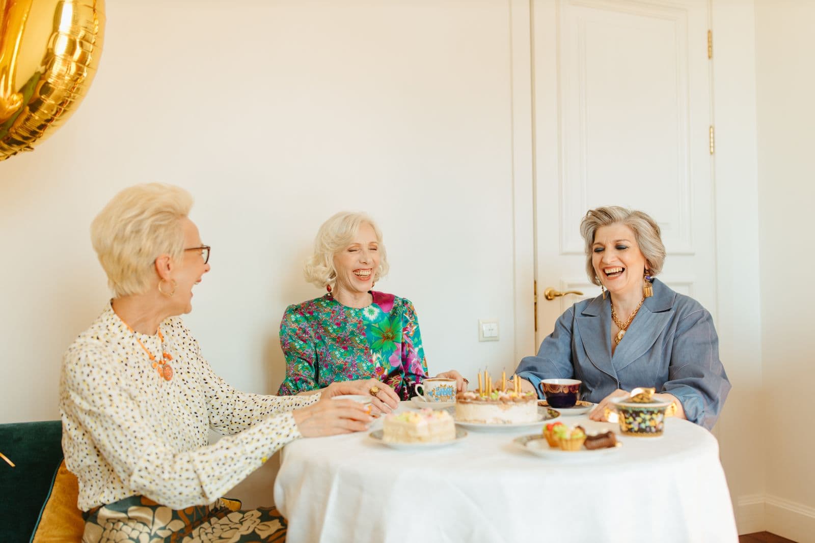 Drei Seniorinnen lachen gemeinsam am Kaffeetisch