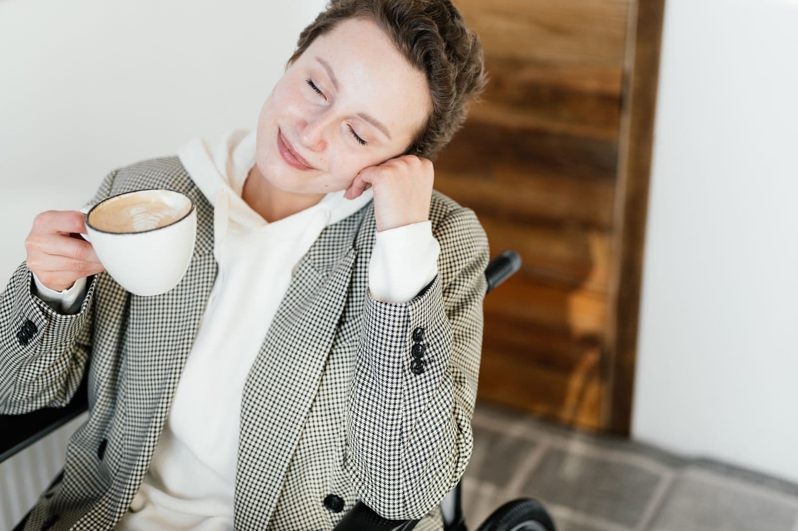 Lächelnde Frau im Rollstuhl mit einer Tasse Kaffee